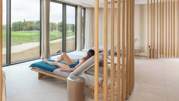 Ein Spa-Raum mit großen Fenstern, einer Massageliege und einer Holzwand.