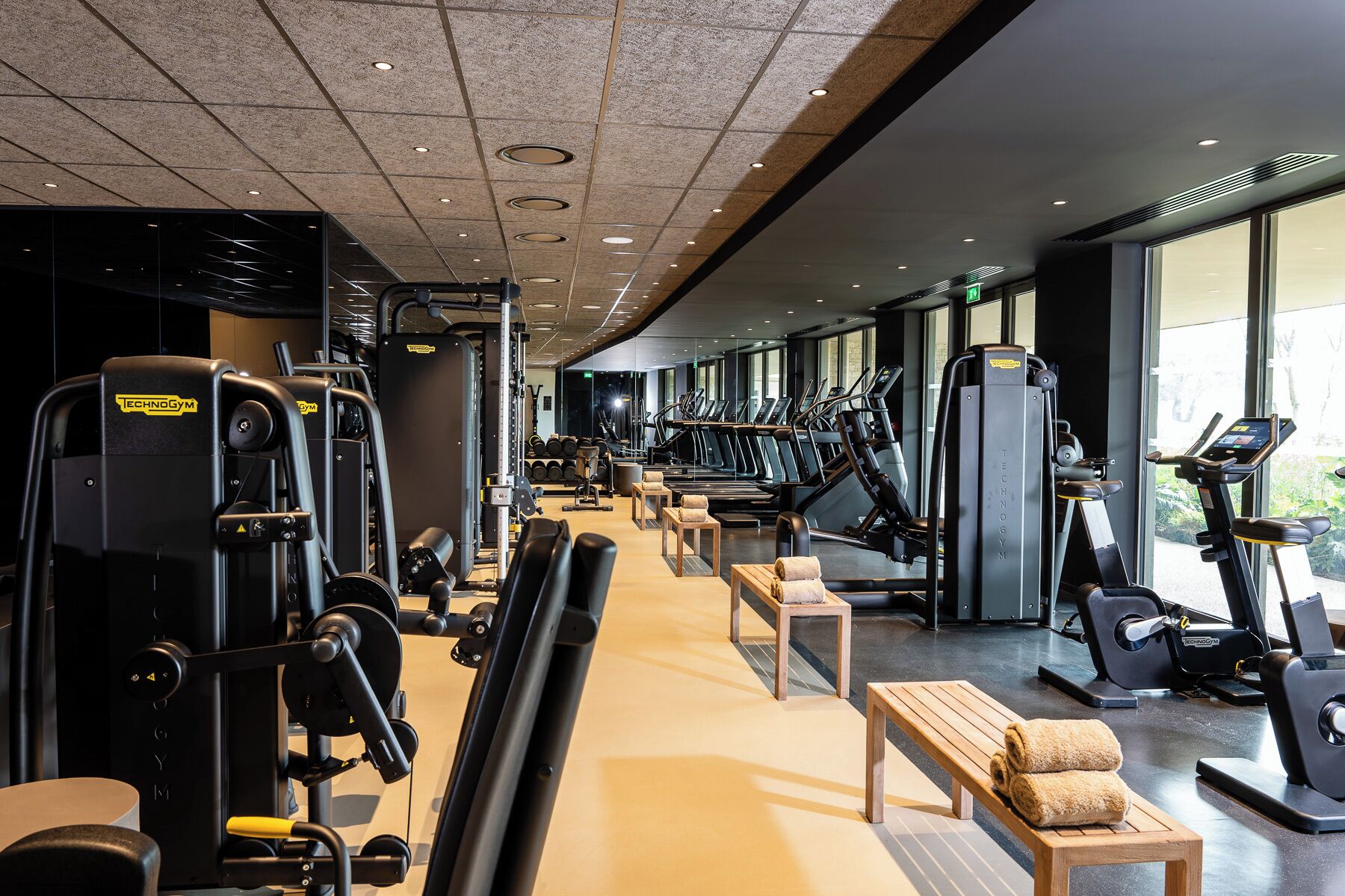 A gym with cardio machines, weightlifting equipment, and benches.