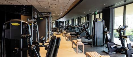A gym with cardio machines, weightlifting equipment, and benches.