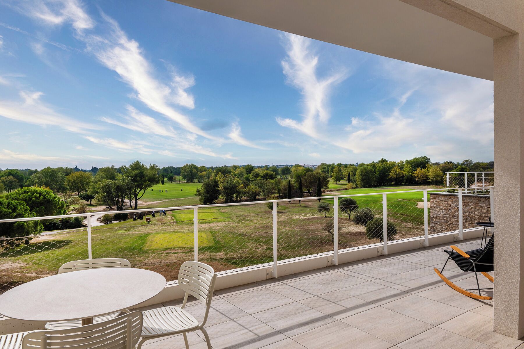 Un balcó amb vista a un camp de golf, una taula i cadires.