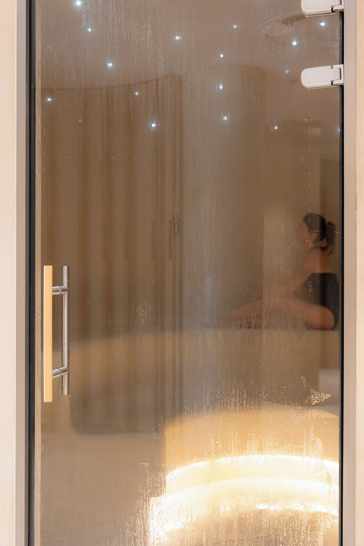 A glass door with a metal handle and a reflection of a person.