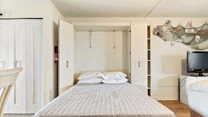 A bedroom with a bed, a television, a wardrobe, and a wall decoration. - Studio with prime location next to Beach, Jolly Rogers and Boardwalk (Ocean City)