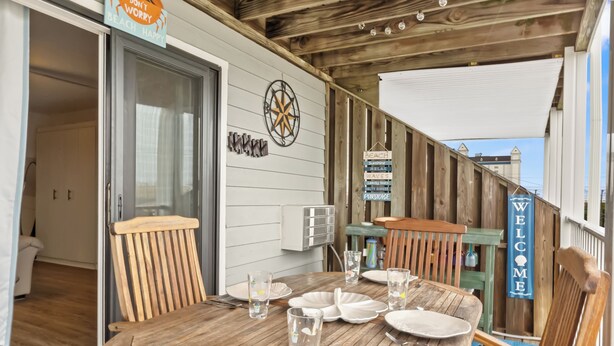 A wooden deck with a table set for four, a compass wall decoration, and a 'Welcome' sign. - Studio with prime location next to Beach, Jolly Rogers and Boardwalk (Ocean City)