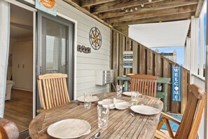 A wooden deck with a table set for four, a compass wall decoration, and a 'Welcome' sign. - Studio with prime location next to Beach, Jolly Rogers and Boardwalk (Ocean City)
