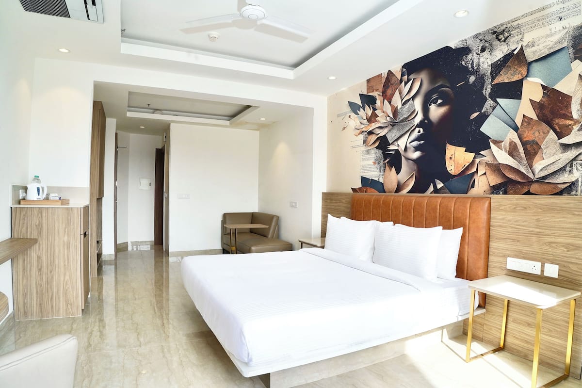 A modern hotel room with a large bed, a wooden headboard, a bedside table, and a ceiling fan.