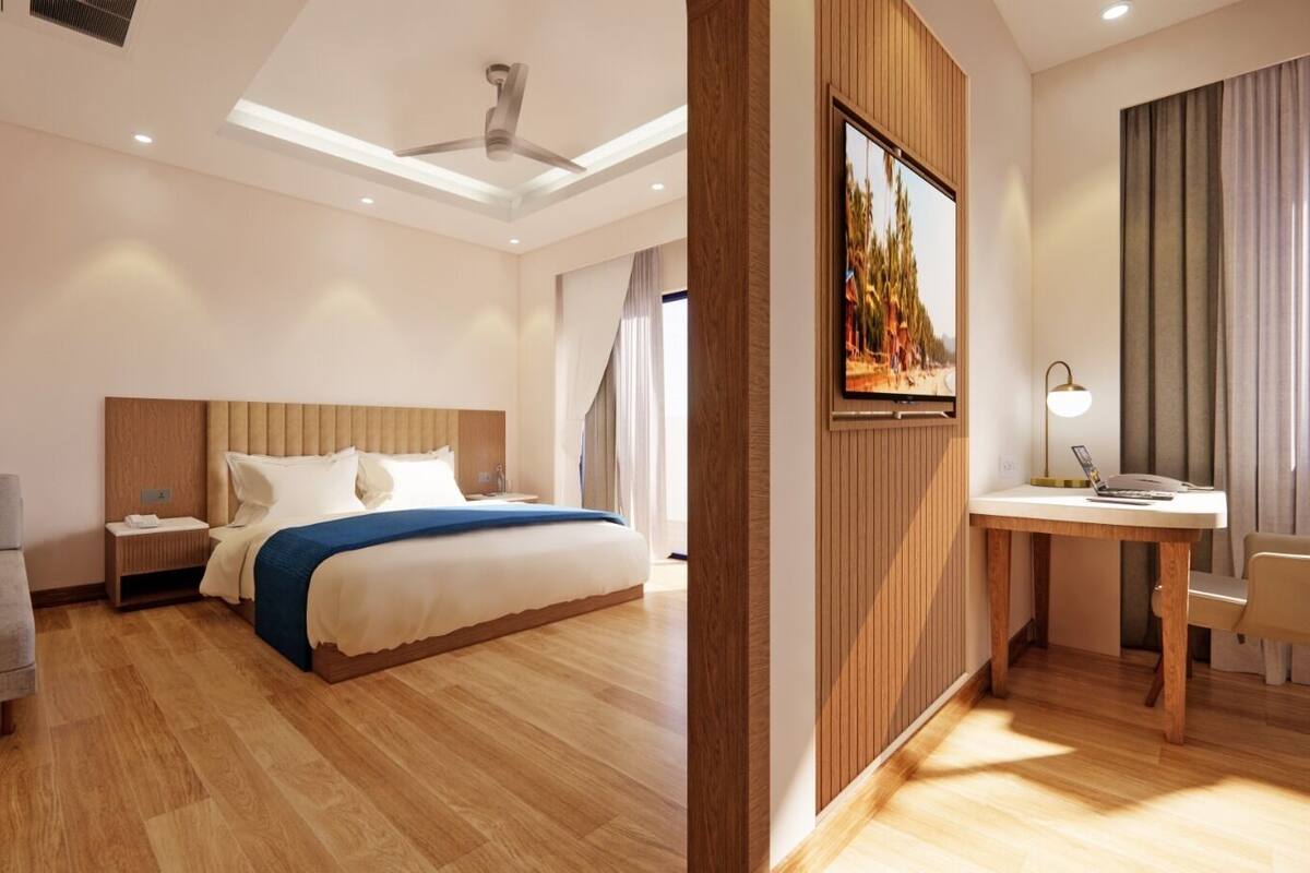 A modern hotel room with a bed, a desk, a sofa, and a large window.