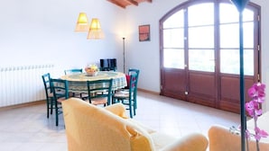 Un coin repas avec une table ronde, des chaises et une lampe. Une grande fenêtre offre une vue sur l’extérieur.