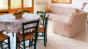 Un coin repas avec une table ronde, des chaises et des lampes suspendues. On y trouve également un canapé et un tableau au mur.