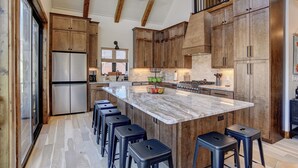 Una cocina moderna con armarios de madera, una isla de mármol y taburetes de bar.