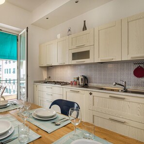 A modern kitchen with light wood cabinets, a gas stove, and a patterned backsplash. - Bright Apartment in San Martino by Wonderful Italy (Genoa)