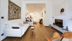 Ein modernes Wohnzimmer mit einem weißen Sofa, einem Couchtisch und einem Fernseher auf einem Lowboard.