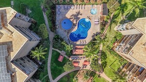 An aerial view of a resort with multiple swimming pools, lounge areas, and palm trees.
