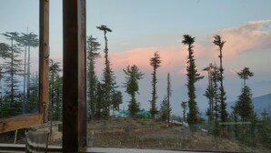 A view through a window of a forested area with tall trees and a distant mountain range. - Ahistay Homes, Fagu (Fagu)