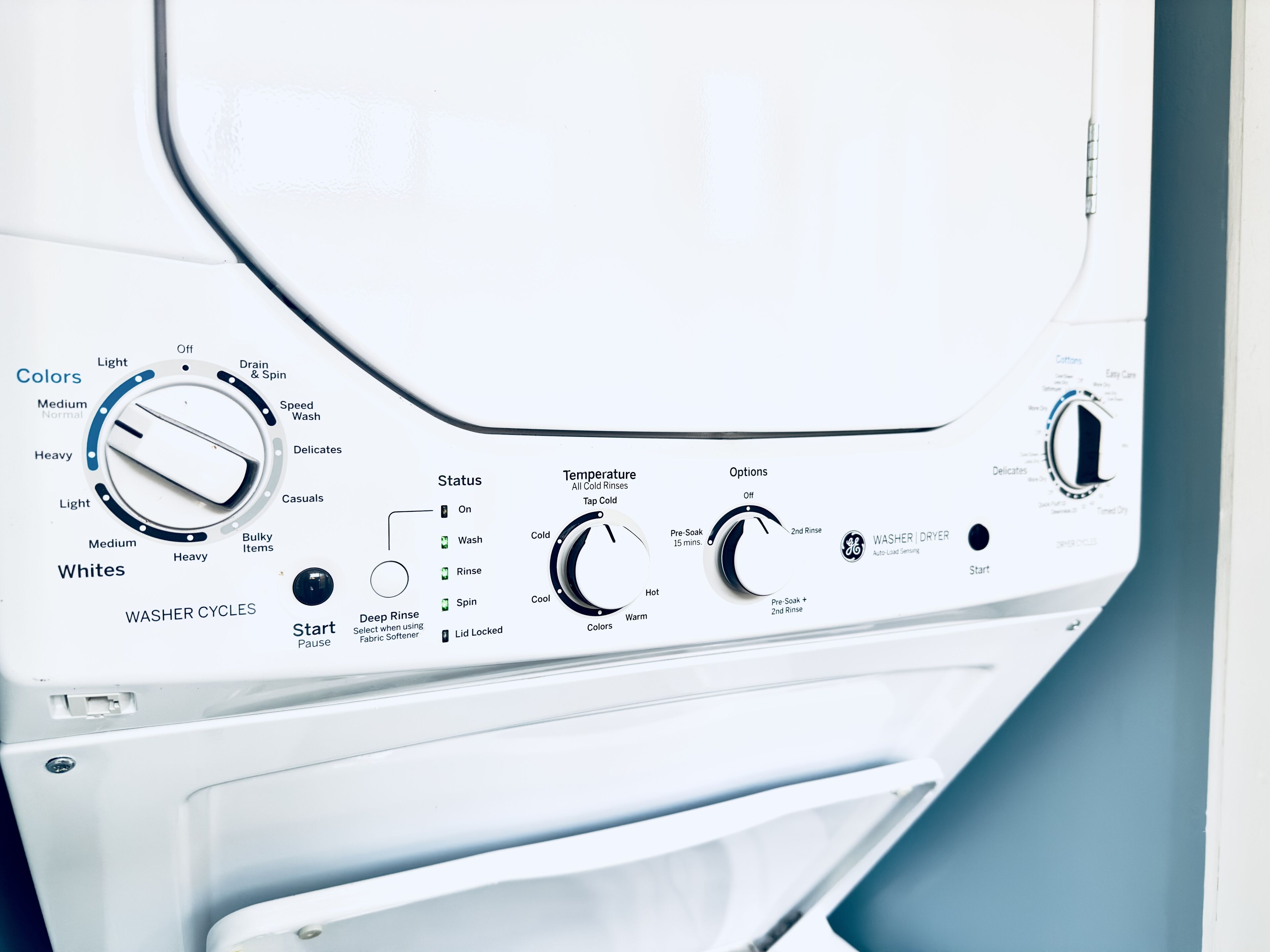 A front view of a white washing machine with control knobs for selecting wash cycles, temperature, and options.