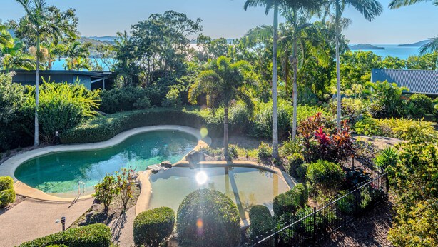 A pool surrounded by lush greenery and palm trees, with a clear view of the sea in the background. - Anchorage 3, Anchorage 3 on Hamilton Island (Hamilton Island)