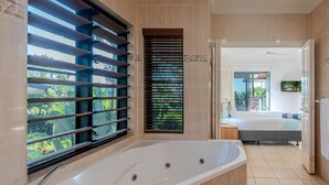 A modern bathroom with a large bathtub, a shower area, and a view of the outdoors through a window with blinds. - Anchorage 3, Anchorage 3 on Hamilton Island (Hamilton Island)