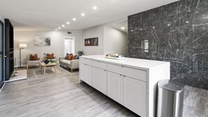 Une cuisine moderne avec des meubles blancs, un pare-feu en marbre et un îlot central.