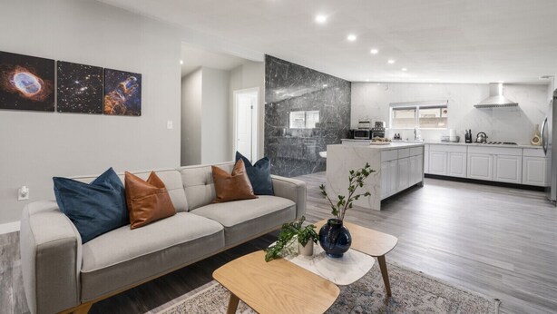 Un salon moderne avec un canapé, une table basse et une œuvre d’art accrochée au mur.