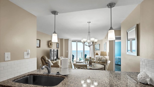 Eine moderne Küche mit Granitarbeitsplatten, einer Spüle und einem Essbereich mit einer Chandelier.
