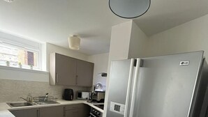 A compact kitchen with a stainless steel refrigerator, a microwave, and a stove. - The M Rooms (Shotts)