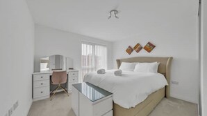 Ein modernes Schlafzimmer mit Bett, Nachttischen, Schreibtisch und Stuhl.