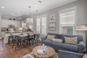 A modern kitchen with white cabinets, a dining area with a wooden table and chairs, and a gray sofa with patterned cushions. - Cozy 3BR Beach Home, Pool & Beach Access ~ Blue Lagoon, Seacrest Beach 30A (Panama City Beach)