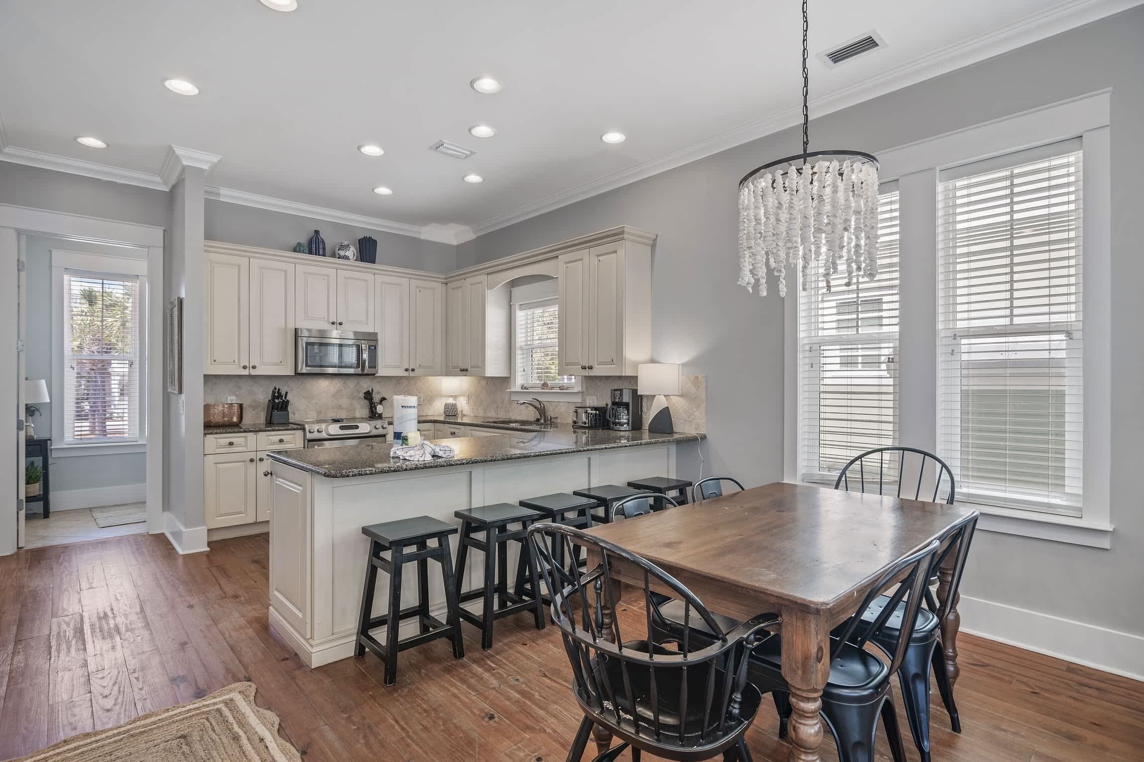 A spacious kitchen with white cabinetry, a central island, and a dining area with a wooden table and chairs.