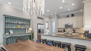 Una cocina moderna con armarios blancos, un refrigerador de acero inoxidable y una encimera de granito.