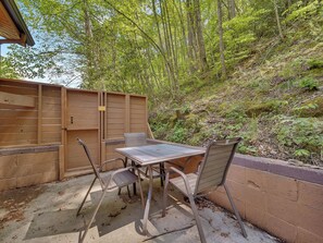 Un patio exterior con una mesa y sillas, rodeado por una valla de madera y un muro de ladrillo.