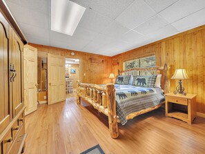 Un dormitorio con paneles de madera, una cama, una mesita de noche y un armario de madera.
