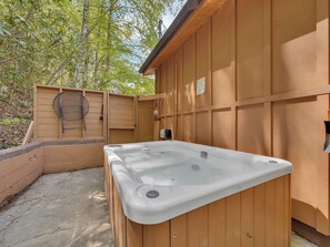 Cerramiento de madera para spa con jacuzzi, valla de madera y portón metálico.