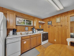 A kitchen with wooden cabinets, a stove, a dishwasher, and a coffee maker.