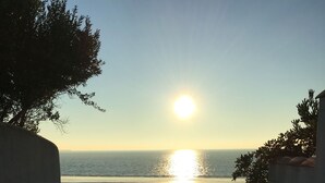 Escadaria que leva a uma praia, com vista para o oceano e o sol se pondo ao longe.
