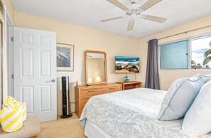 A bedroom with a bed, dresser, mirror, and a ceiling fan.
