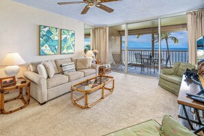 A spacious living room with a sofa, coffee table, and a balcony with a view of the ocean.