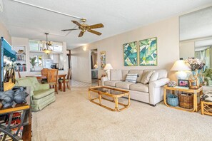 A spacious living room with a sofa, coffee table, and a dining area with chairs.