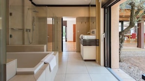 Un baño moderno con ducha envuelta en vidrio, una bañera independiente y un tocador con lavamanos y espejo.