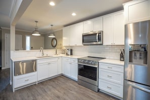 Una cocina moderna con armarios blancos, electrodomésticos de acero inoxidable y suelo de madera.