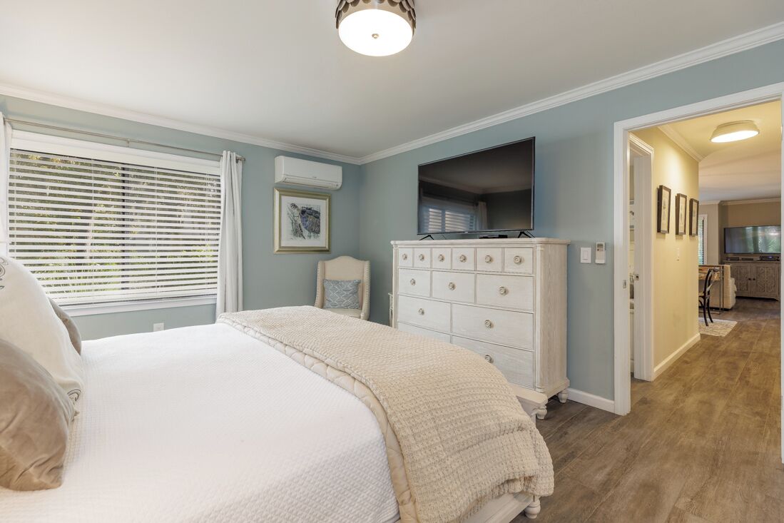 Un dormitorio con cama, cómoda y un pasillo que lleva a una cocina.
