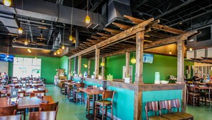 A restaurant with wooden tables and chairs, a counter with a green wall, and hanging pendant lights. - New to Seascape Vacations in a fantastic location! Small dogs allowed! (Miramar Beach)