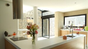 A modern kitchen with a white countertop, a built-in stove, and a large window.