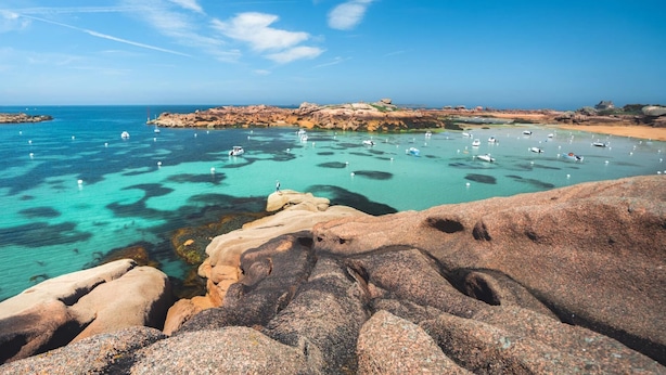 A coastal landscape with clear turquoise waters, rocky formations, and boats anchored in the bay. - Studio Cosy - plein coeur de Lannion (Lannion)