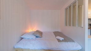 A small, neatly made bed with white linens and a wooden headboard. - Studio Cosy - plein coeur de Lannion (Lannion)
