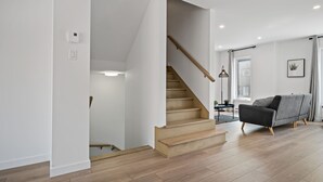 Ein modernes Wohnzimmer mit Treppe, einem grauen Sofa und Holzboden.