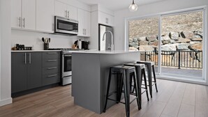 Eine moderne Küche mit weißen Schränken, einem Edelstahlkühlschrank und einer großen Kochinsel mit Barhocker.
