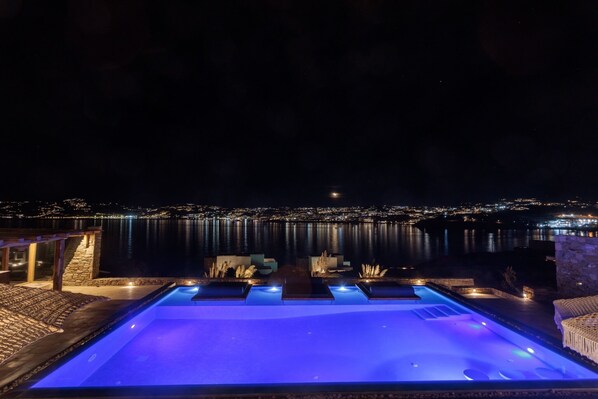 A nighttime view of a swimming pool with a cityscape in the background.