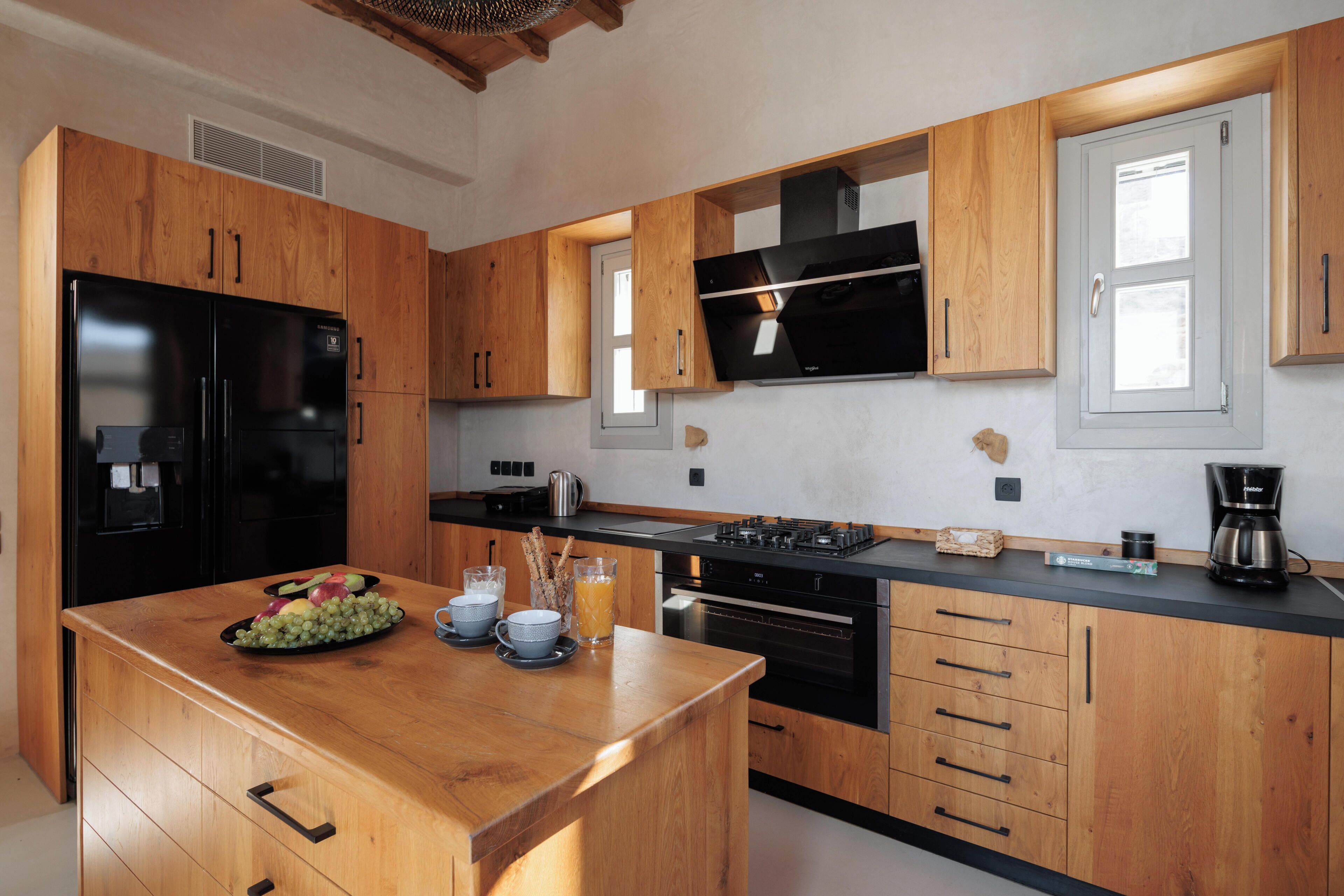 A modern kitchen with wooden cabinets, a black refrigerator, a stove, and a coffee maker.