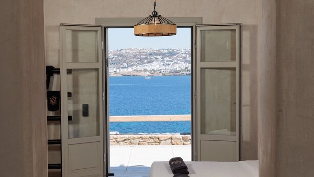 A bedroom with a bed, a wooden ceiling, and a view of the sea. - Ocean whisper villa with amazing view  (mykonos)