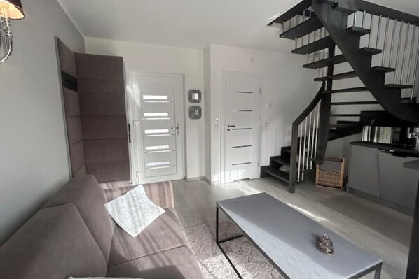 Una sala de estar moderna con un sofá, una mesa baja y una escalera.