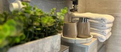 A bathroom with a plant, a towel, and a cup on a counter.